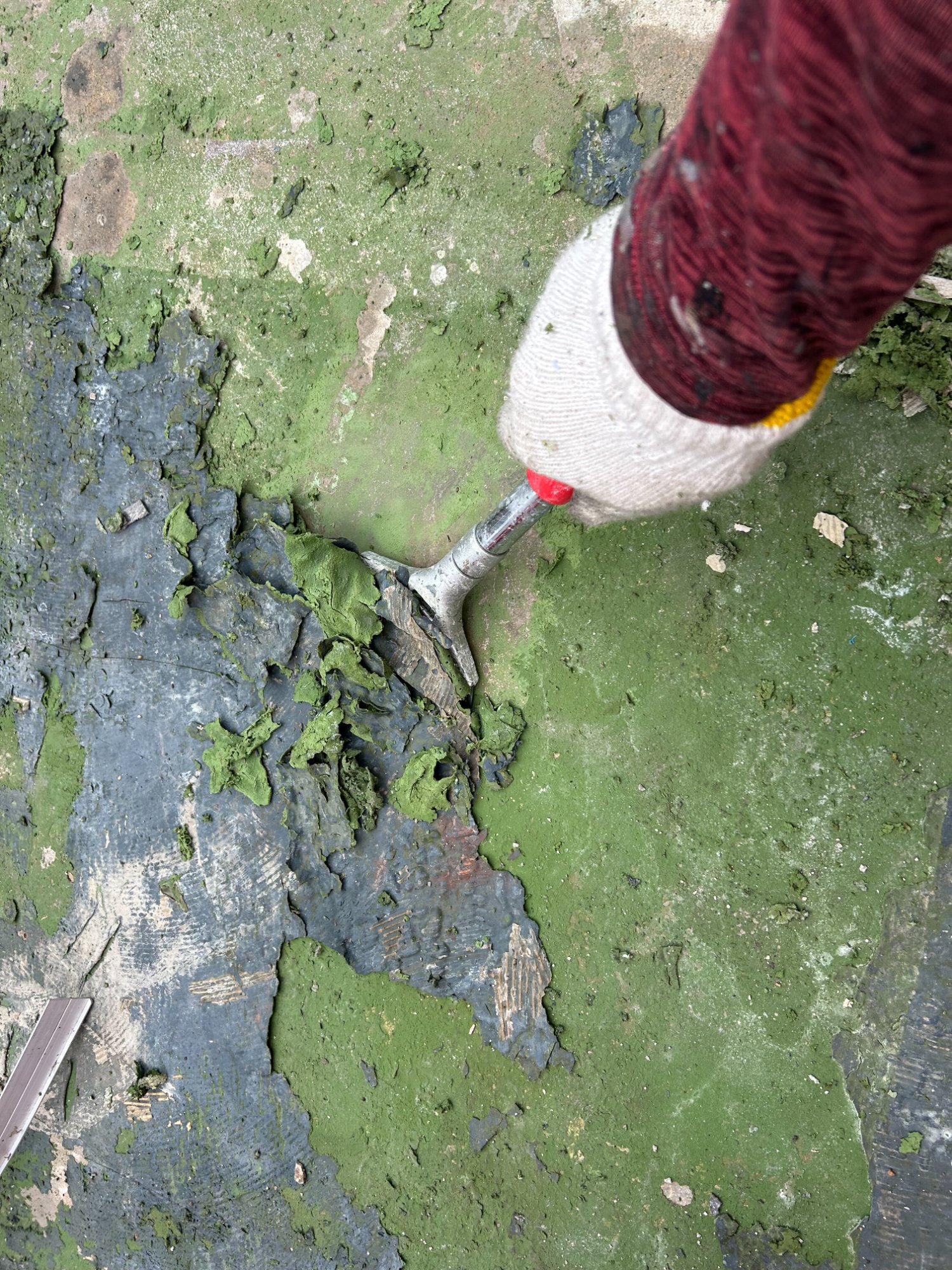 ヘラを使って旧接着剤や劣化したウレタン防水を除去するケレン作業