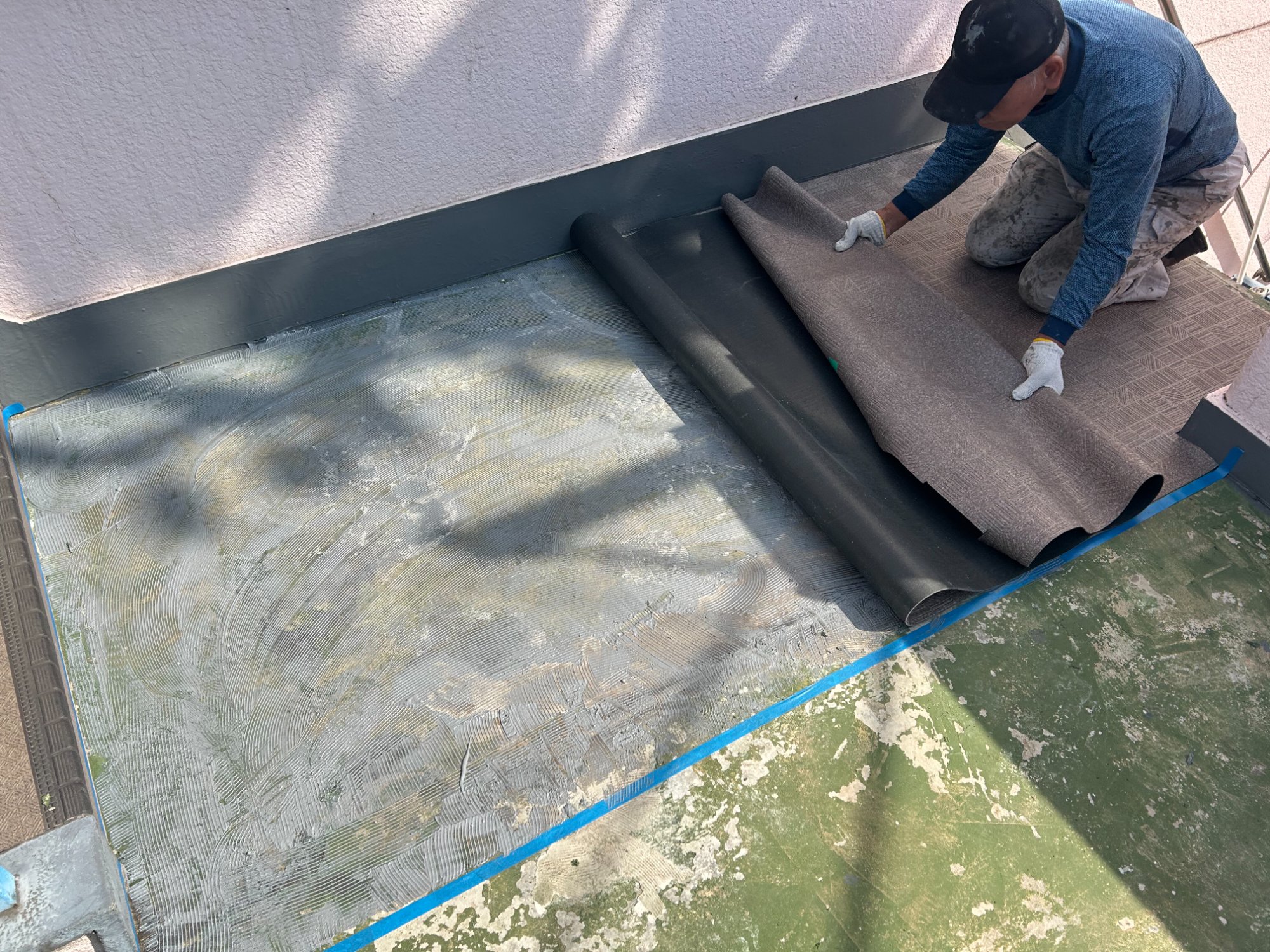 職人が新しい長尺シートを貼り付けている作業風景
