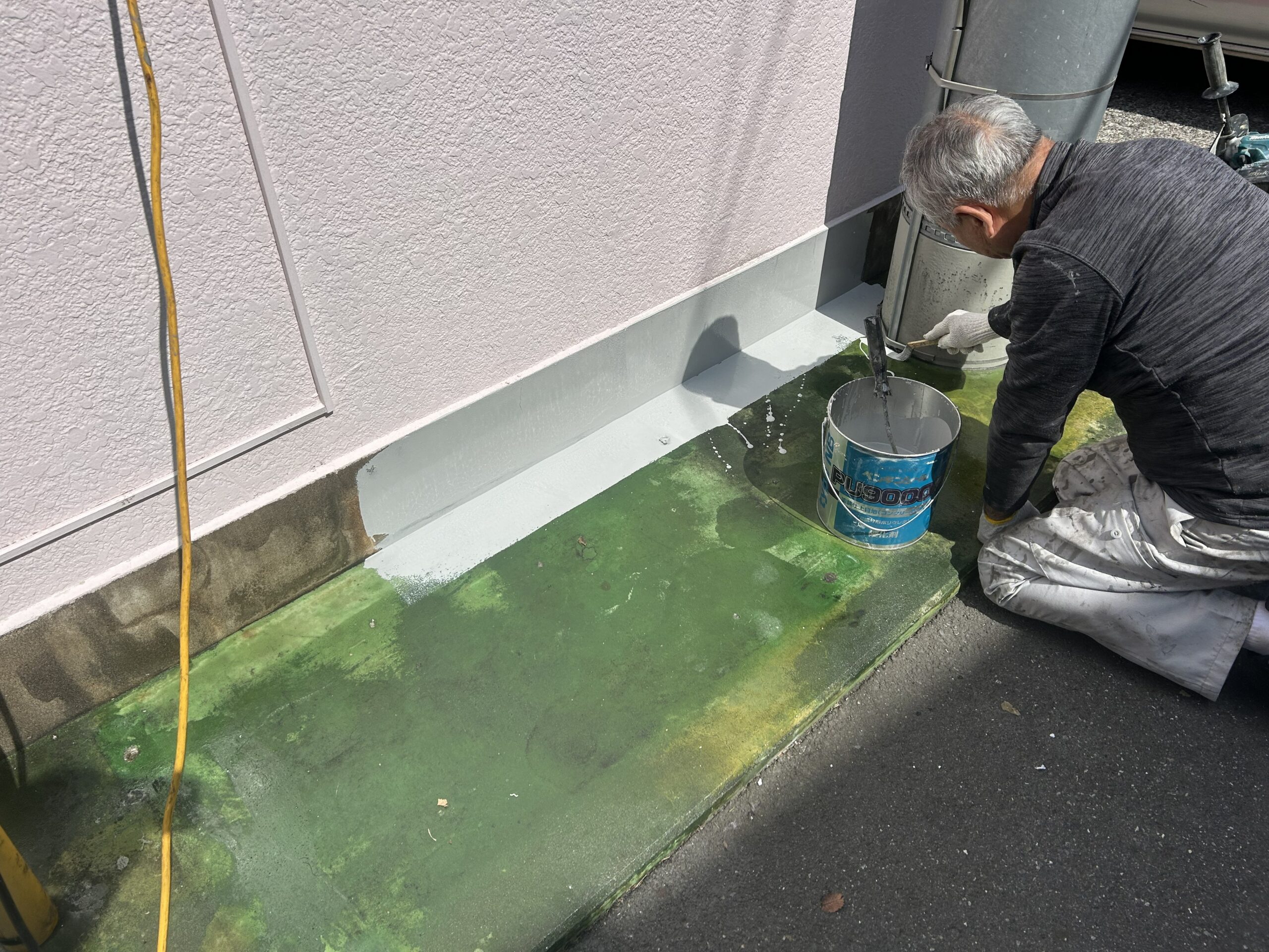 建物入口で職人がプライマーを塗布している様子