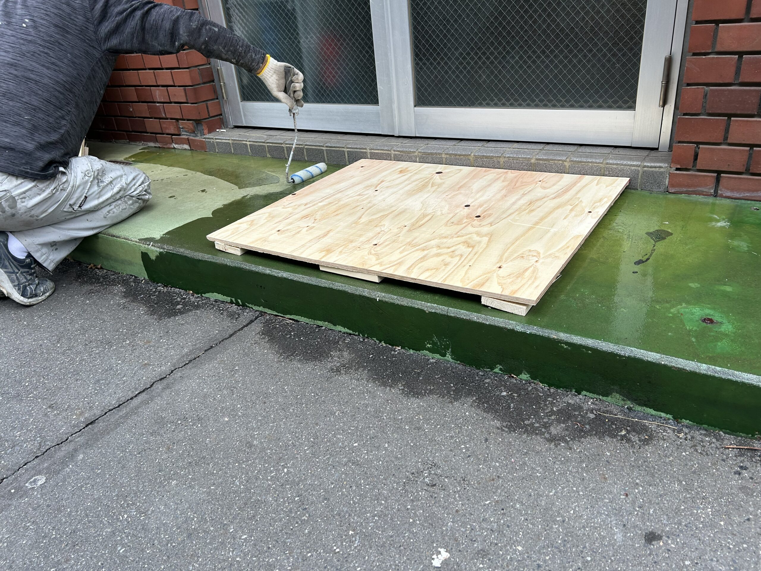 塗床工事中に木板で居住者の通行路を確保している様子