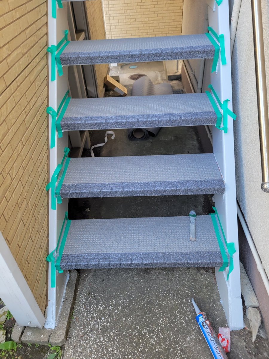 階段へのタキステップ貼り付け作業中 養生テープで端部を固定