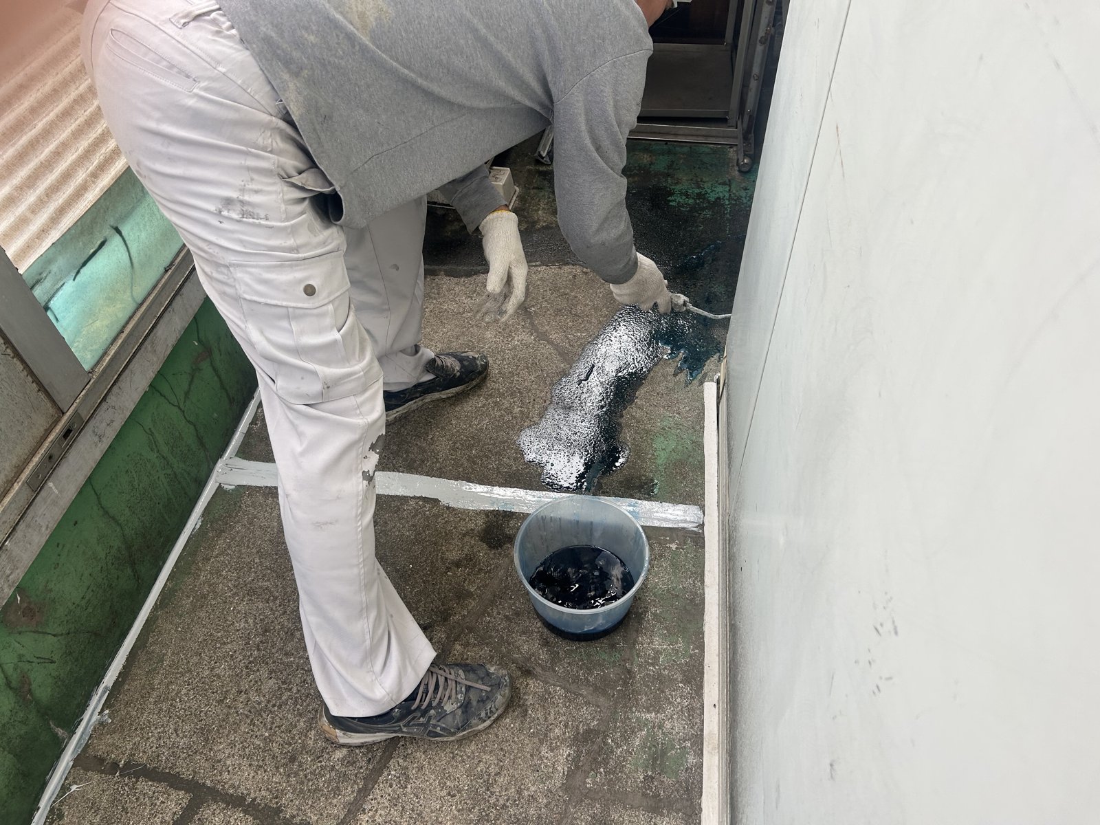ベランダ防水工事でプライマーを塗布する職人