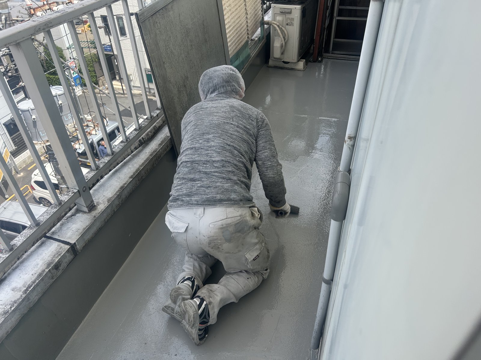 ベランダにトップコートを塗布する防水工事の様子