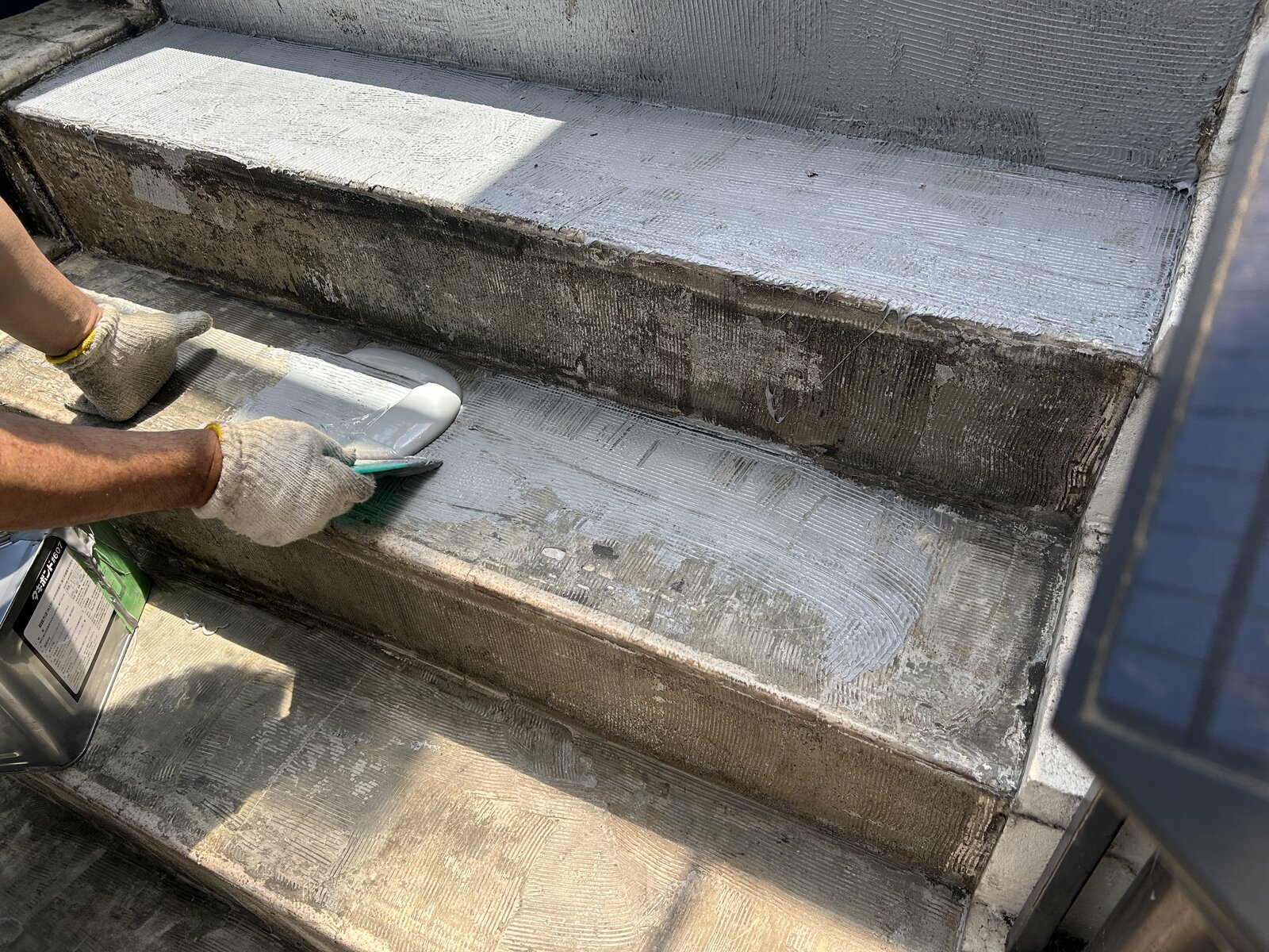 階段の踏面と蹴上げにエポキシ系接着剤をクシゴテで塗布する作業