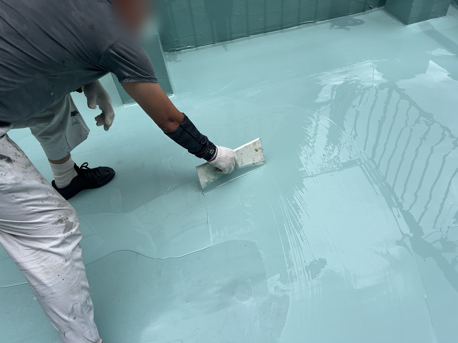 屋上にウレタン防水材の2層目を塗る作業