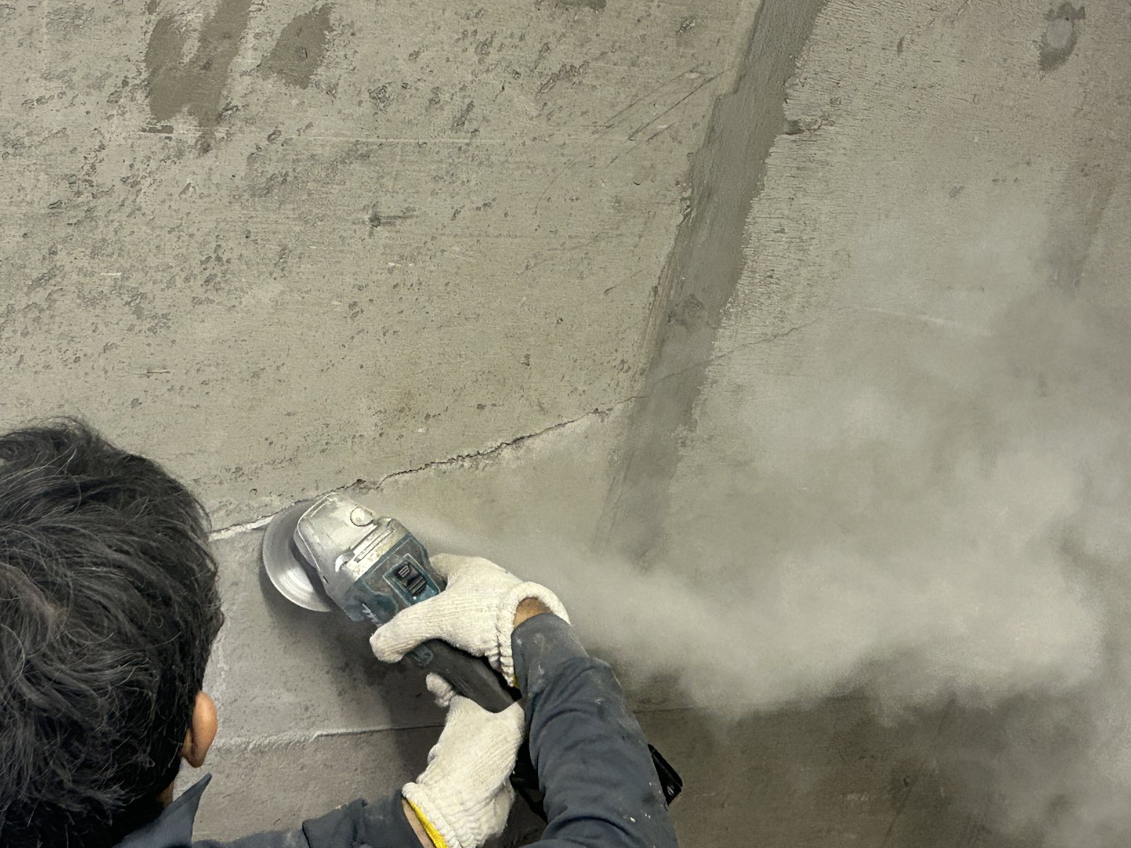 エレベーター室のクラックをディスクグラインダーでVカットする作業