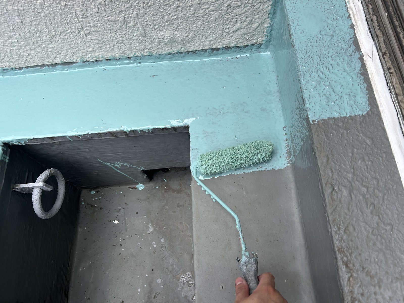 ベランダの立上りにウレタン防水材をローラーで塗る作業