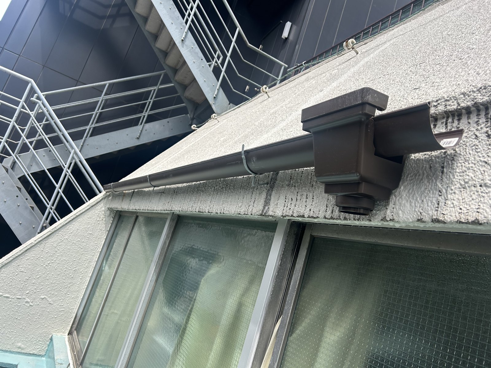 セットバック部の下端に雨どいを取り付けている途中