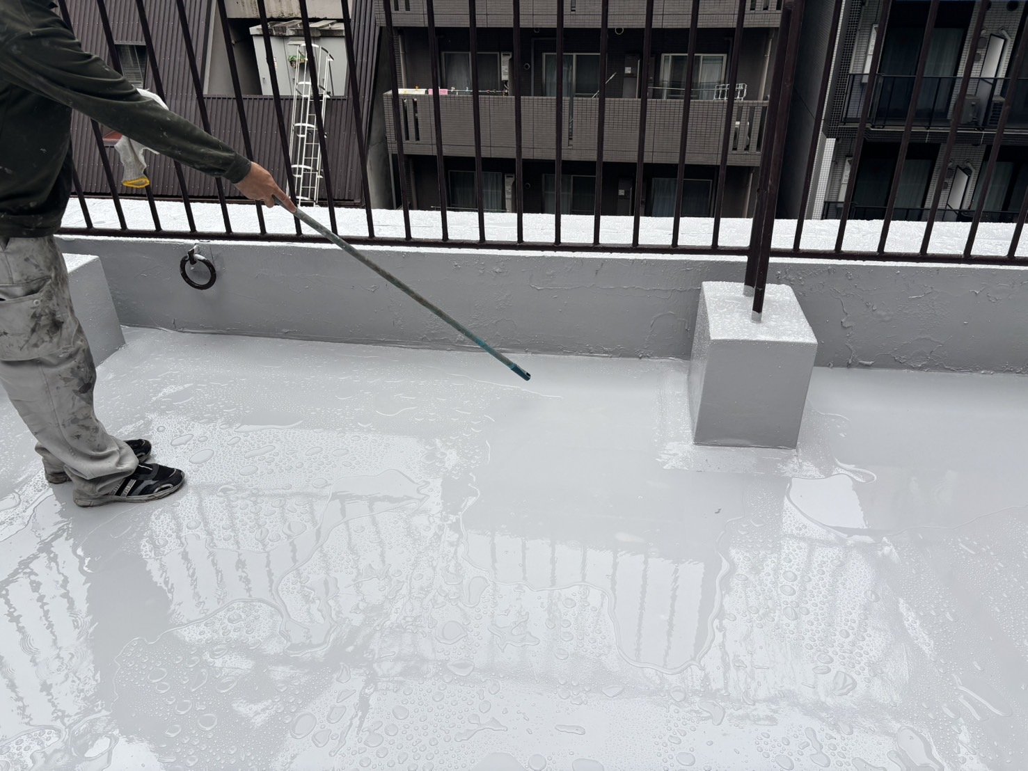 雨のあとの屋上で水溜まりの位置を確認している