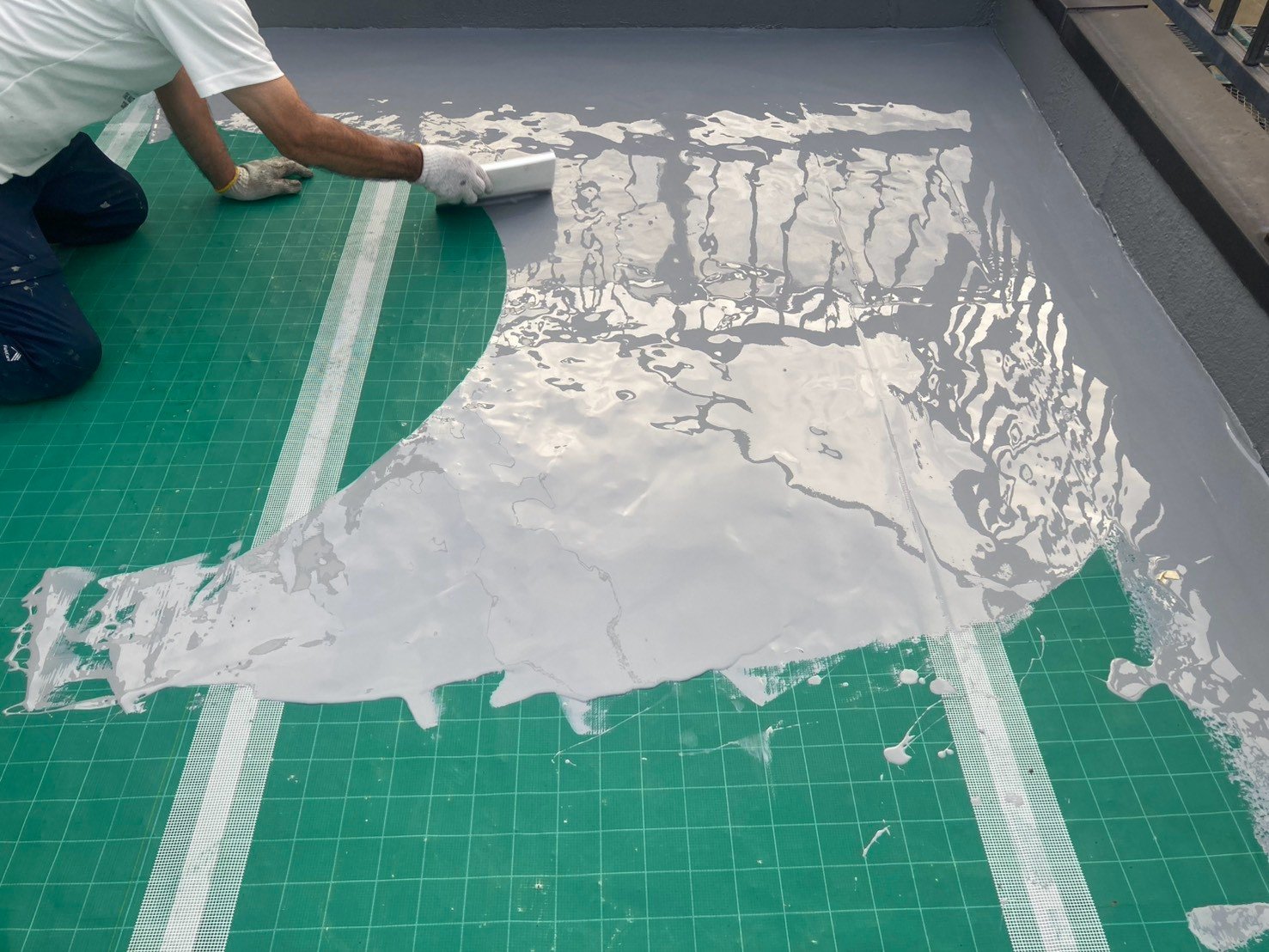 通気緩衝シートの上にウレタン防水材を流して塗り広げる作業